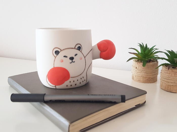 BOXING BEAR MUG. A funny gift for girlfriend. White mug with a bear drawn on it and as a holder it has the arm of the bear extended, with a red glove, as if it was boxing. Bear is looking focused.